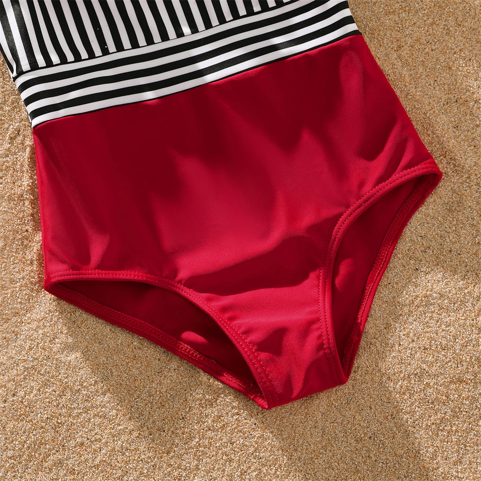 Happy family unit in matching striped swimsuits, ready for summer adventures.