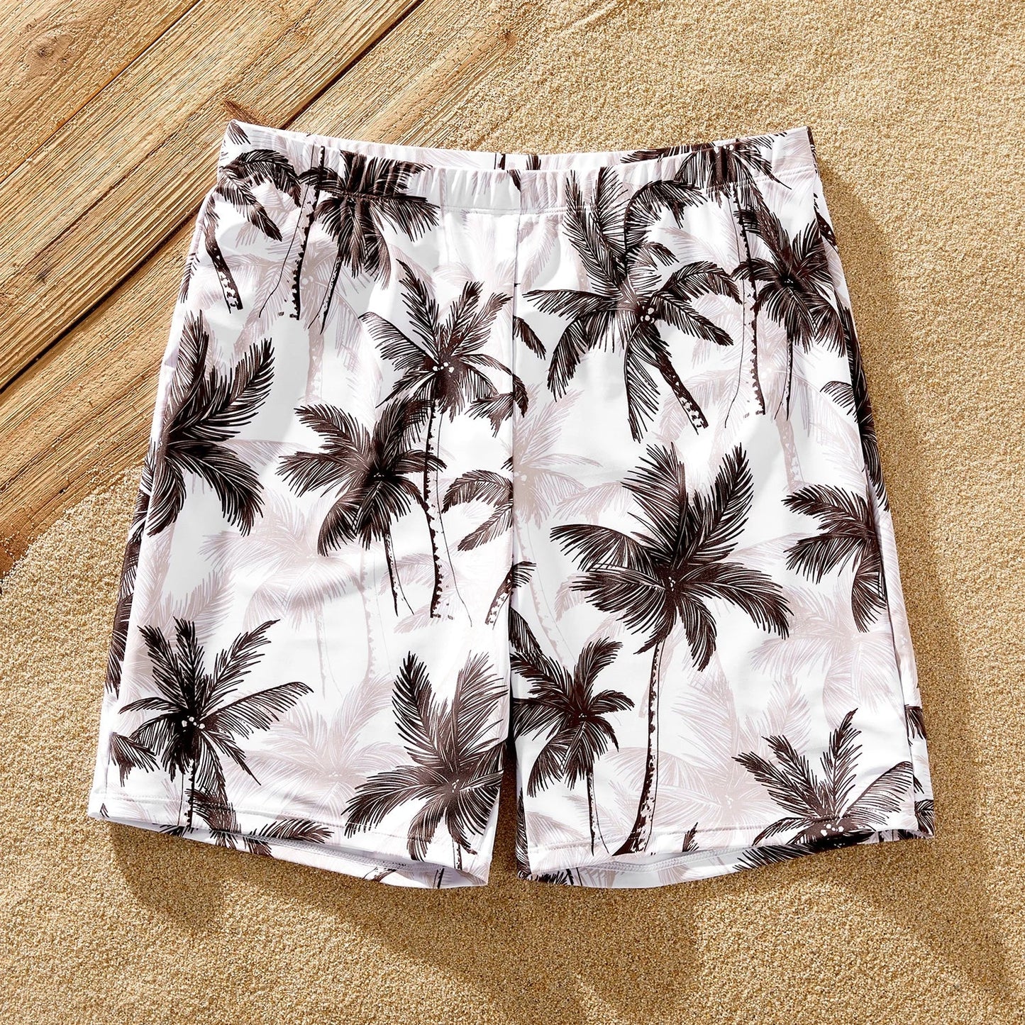 Side view of a matching family set of coconut tree print swimsuits; perfect for poolside fun