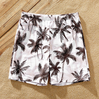 Side view of a matching family set of coconut tree print swimsuits; perfect for poolside fun