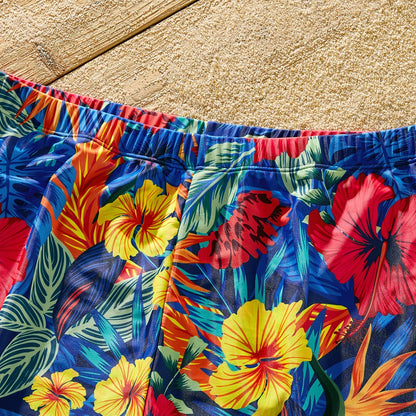 Family in coordinated swimwear: women's scallop design swimsuit and men's floral beach trunks.