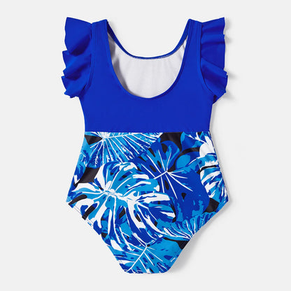 Father and son in coordinating tropical leaf swim trunks, ready for a fun day at the beach.