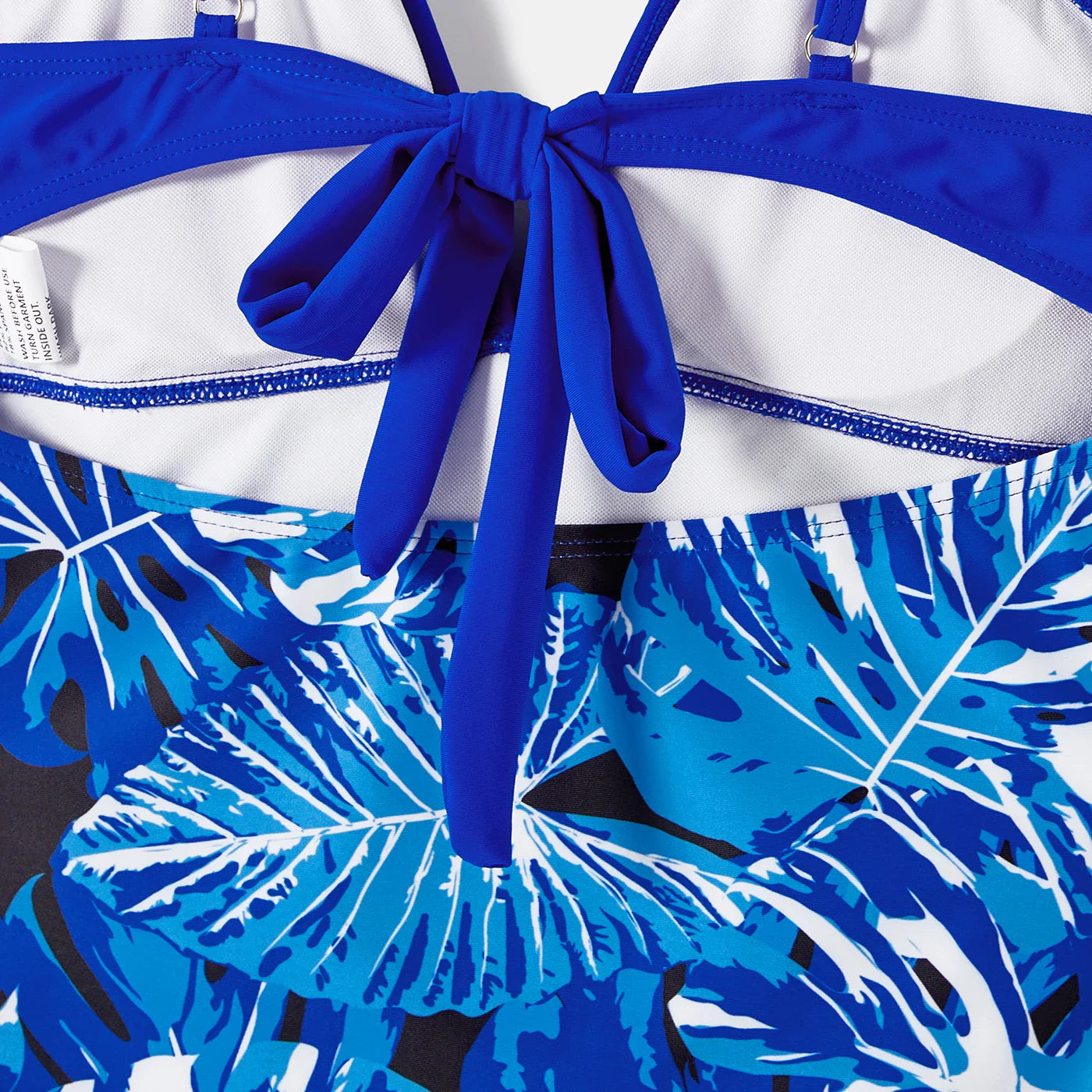 Kids' tropical leaf print swimsuit, one-piece with ruffles, vibrant and playful beachwear.