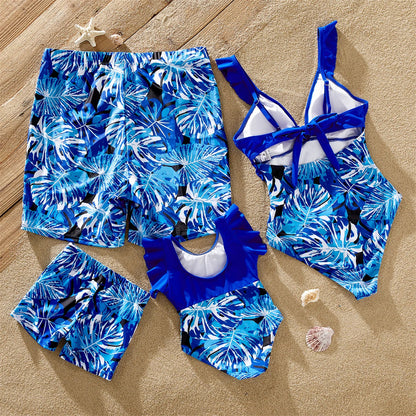 Tropical leaf print men's swim trunks paired with women's and kids' matching ruffle swimsuits, summer vacation.
