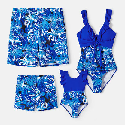 Happy family in tropical leaf print swimsuits, enjoying pool time, perfect for summer fashion.