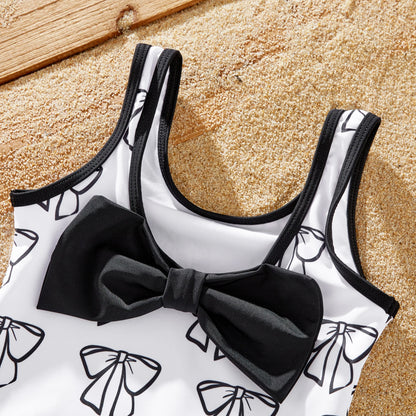 Family matching outfits: 'Love' letter print white bow swimsuit and coordinated swim trunks.