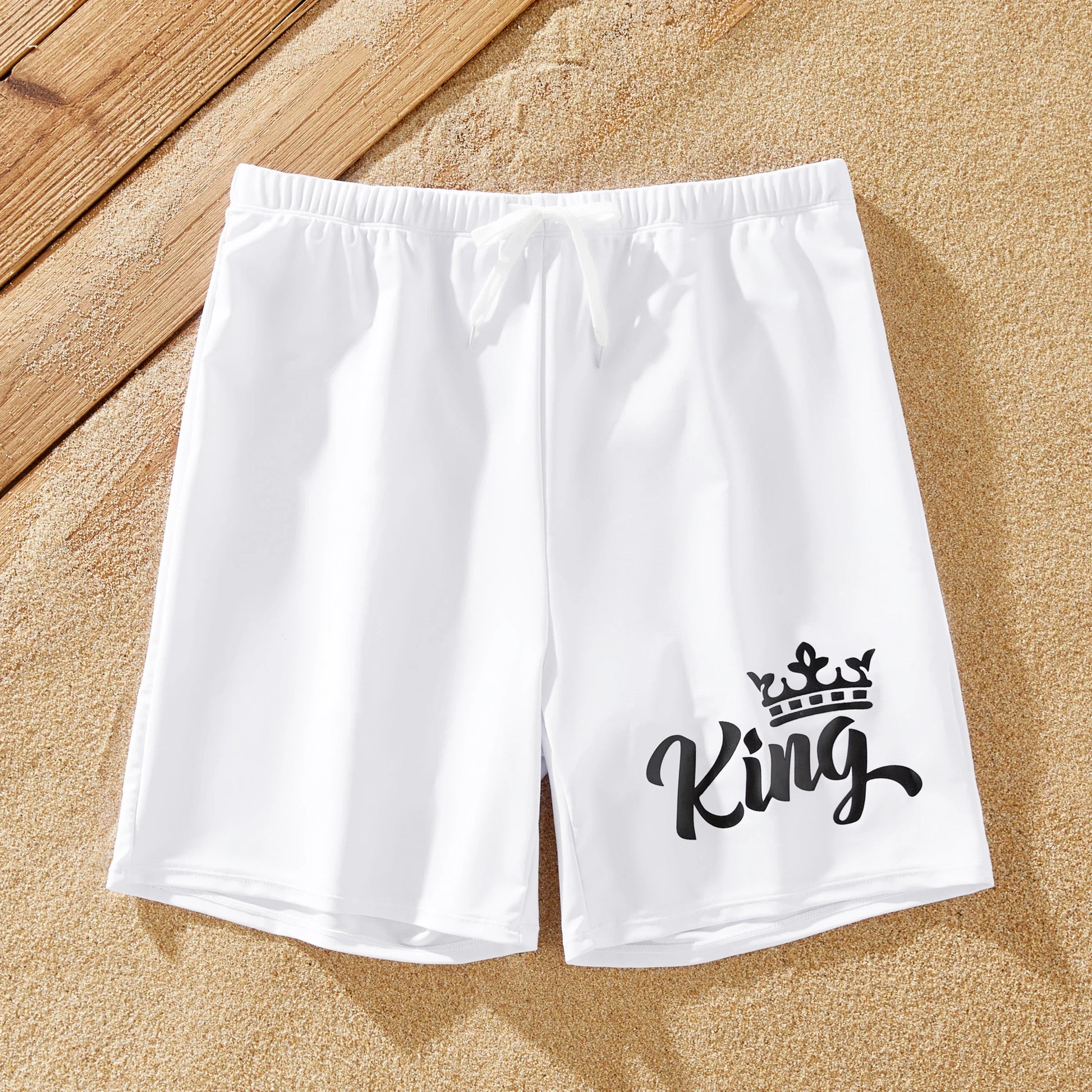 Family matching swimwear: white bow swimsuit for women, white drawstring trunks for men.