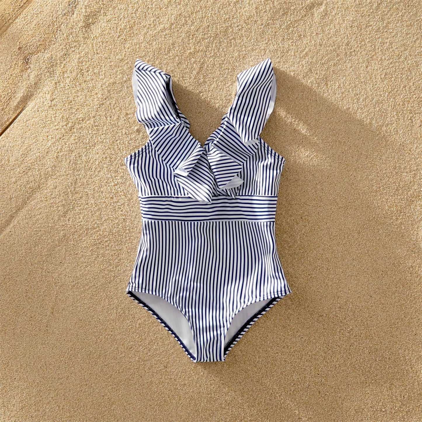 Family wearing striped V-neck flounce matching swimsuits by the ocean, summer fashion