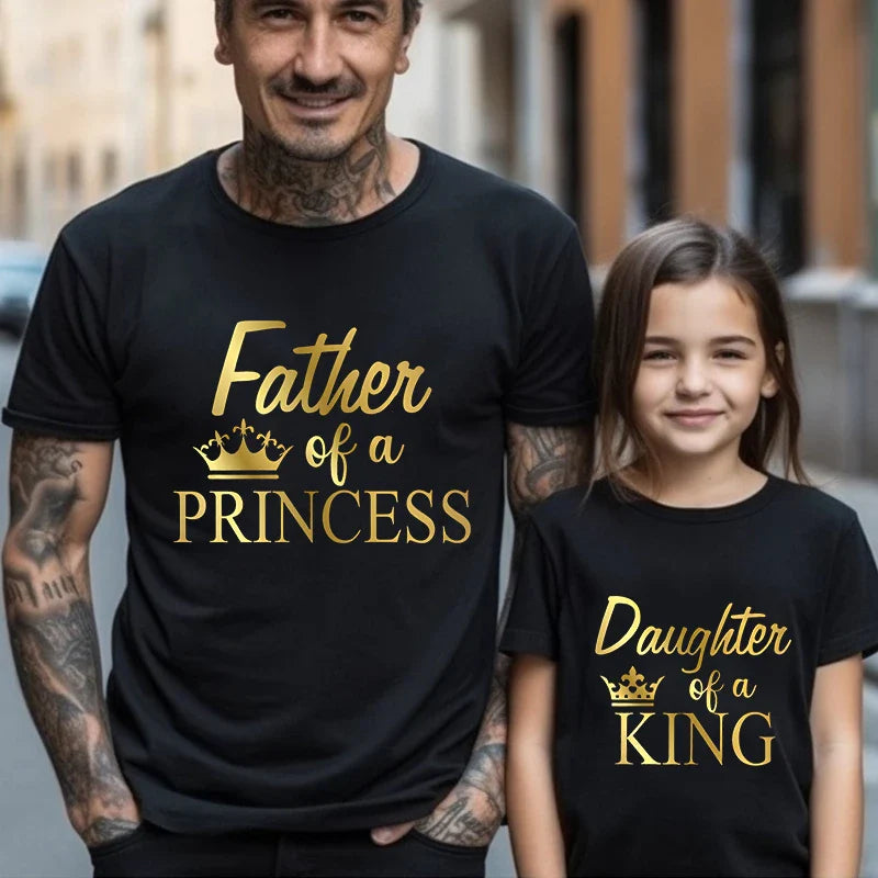 Dad and daughter laughing while wearing their 'Princess King' matching t-shirts, fun family moment.