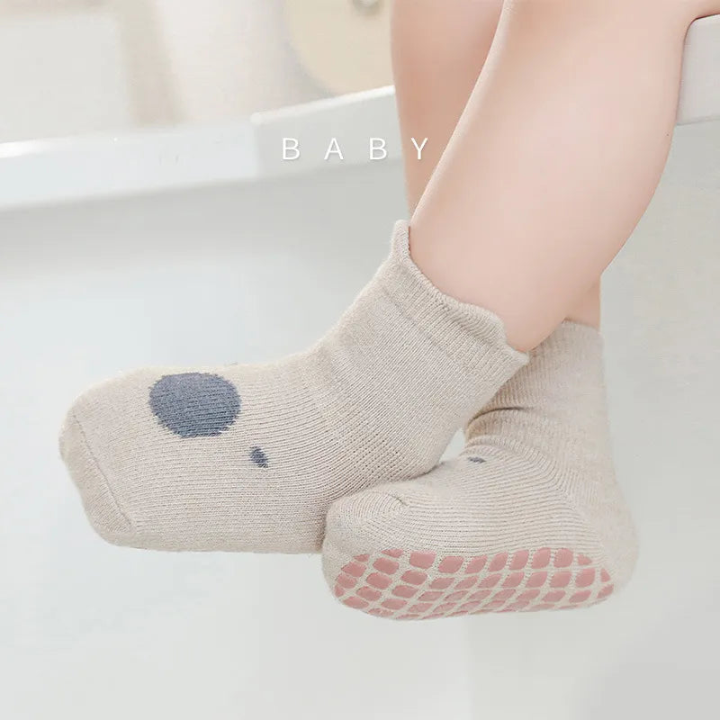Close-up of a pair of yellow anti-slip baby socks with a cute cartoon animal face