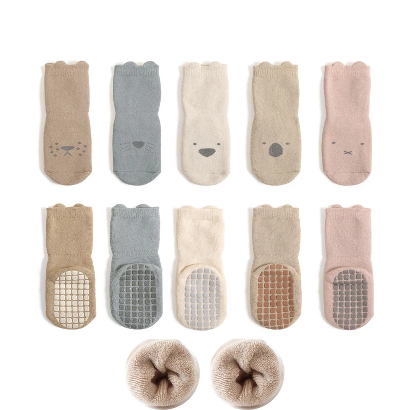Toddler feet wearing anti-slip cartoon socks on a wooden floor, preventing slips