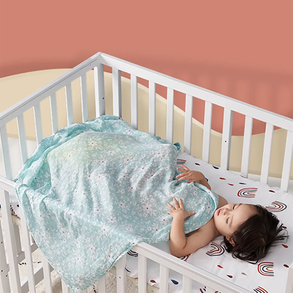Close-up of a white bamboo cotton muslin swaddle blanket with subtle animal print, breathable