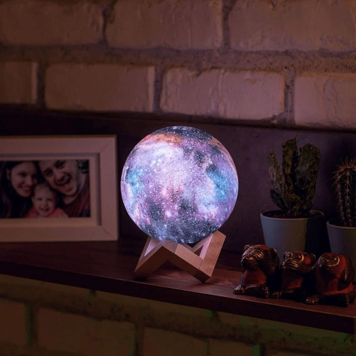 Close-up: Color-changing 3D moon lamp with galaxy texture, illuminated on a minimalist wooden stand.