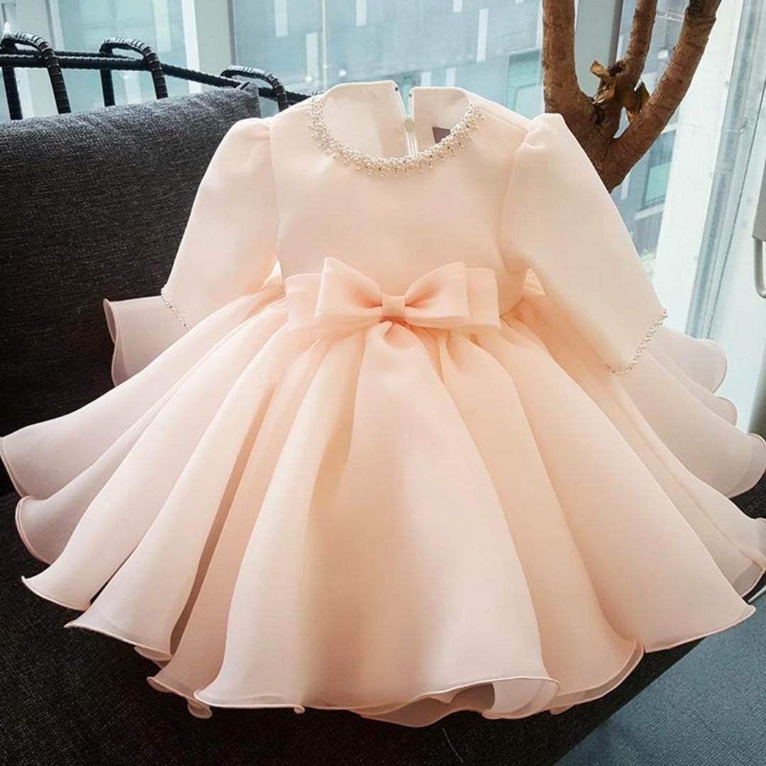 Girl's elegant pearl neckline long sleeve ball gown, perfect for wedding or baptism, close-up on bodice details.