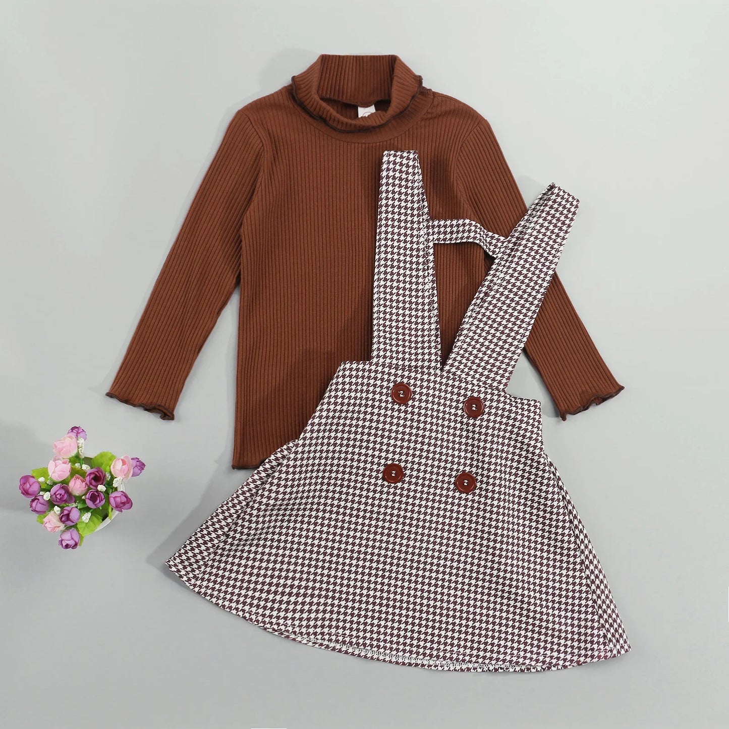 Girls autumn two-piece set featuring a cream turtleneck top and a pleated plaid suspender skirt.