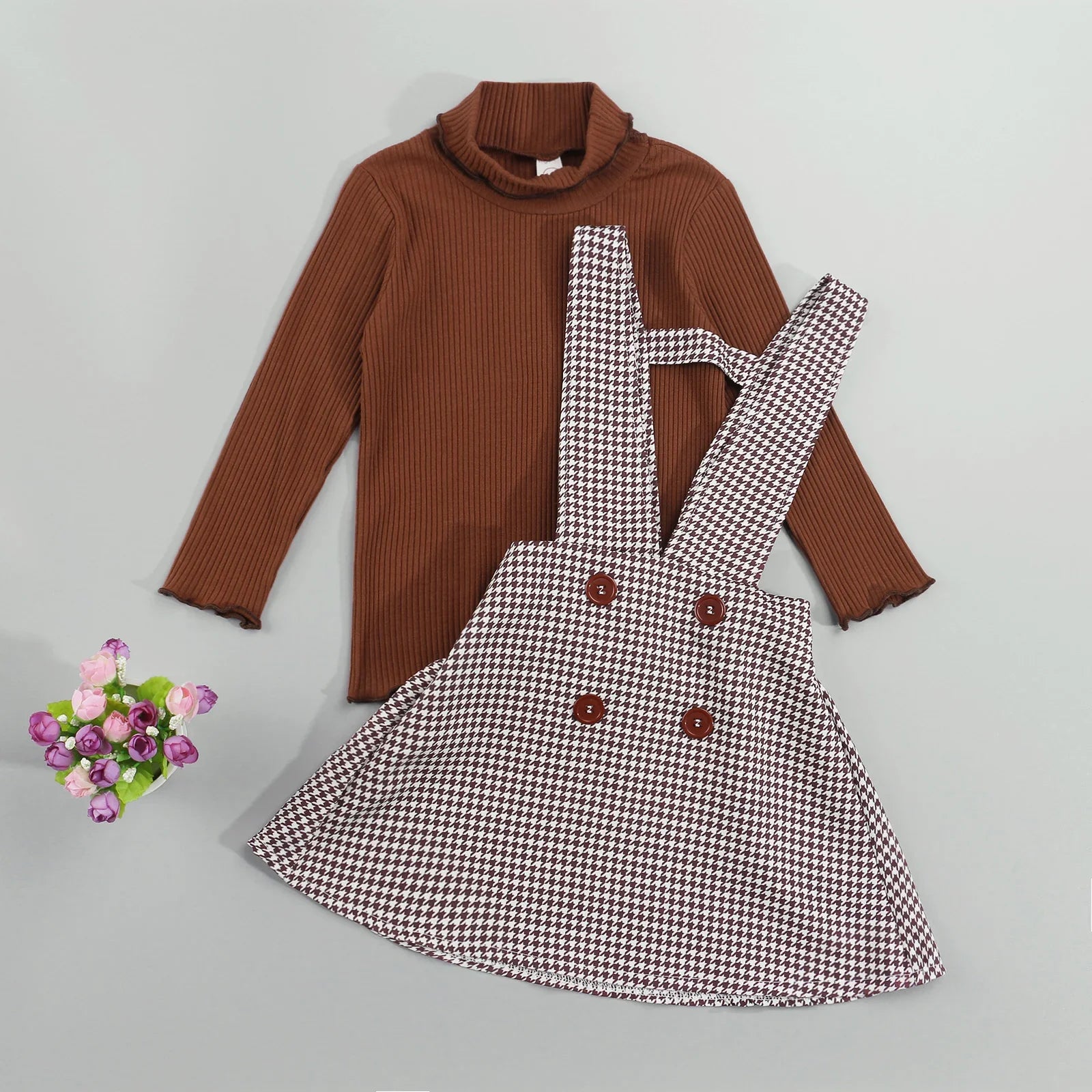 Girls autumn two-piece set featuring a cream turtleneck top and a pleated plaid suspender skirt.