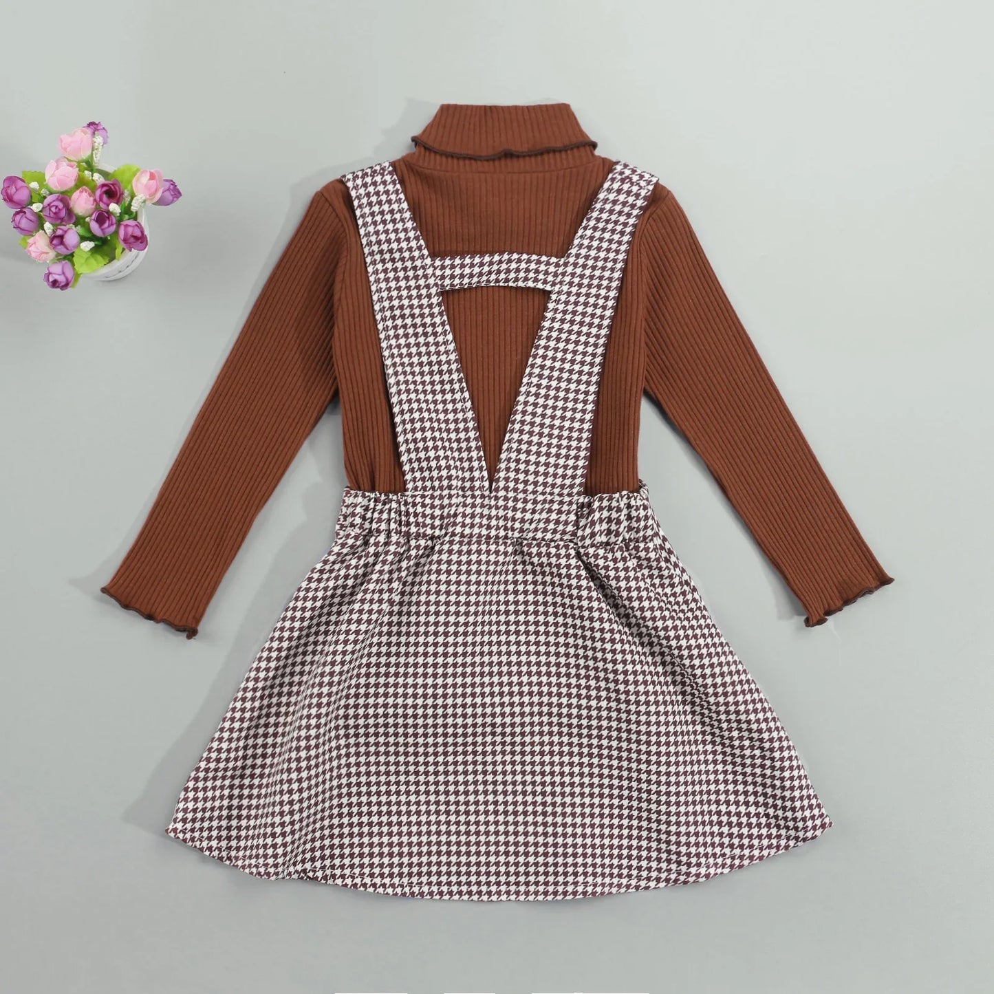 Stylish fall outfit for girls: a cozy long-sleeve turtleneck paired with a cute plaid suspender skirt.