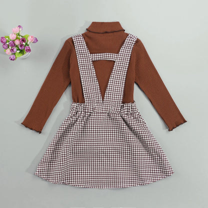 Stylish fall outfit for girls: a cozy long-sleeve turtleneck paired with a cute plaid suspender skirt.
