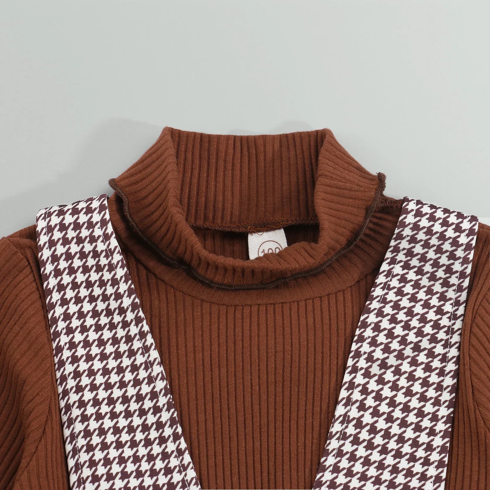 Girl modeling a fall two-piece apparel: a warm long-sleeve top and a charming plaid suspender dress.