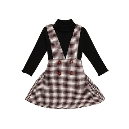 Full view of a girls' autumn outfit: a solid turtleneck and a stylish plaid suspender skirt for kids.