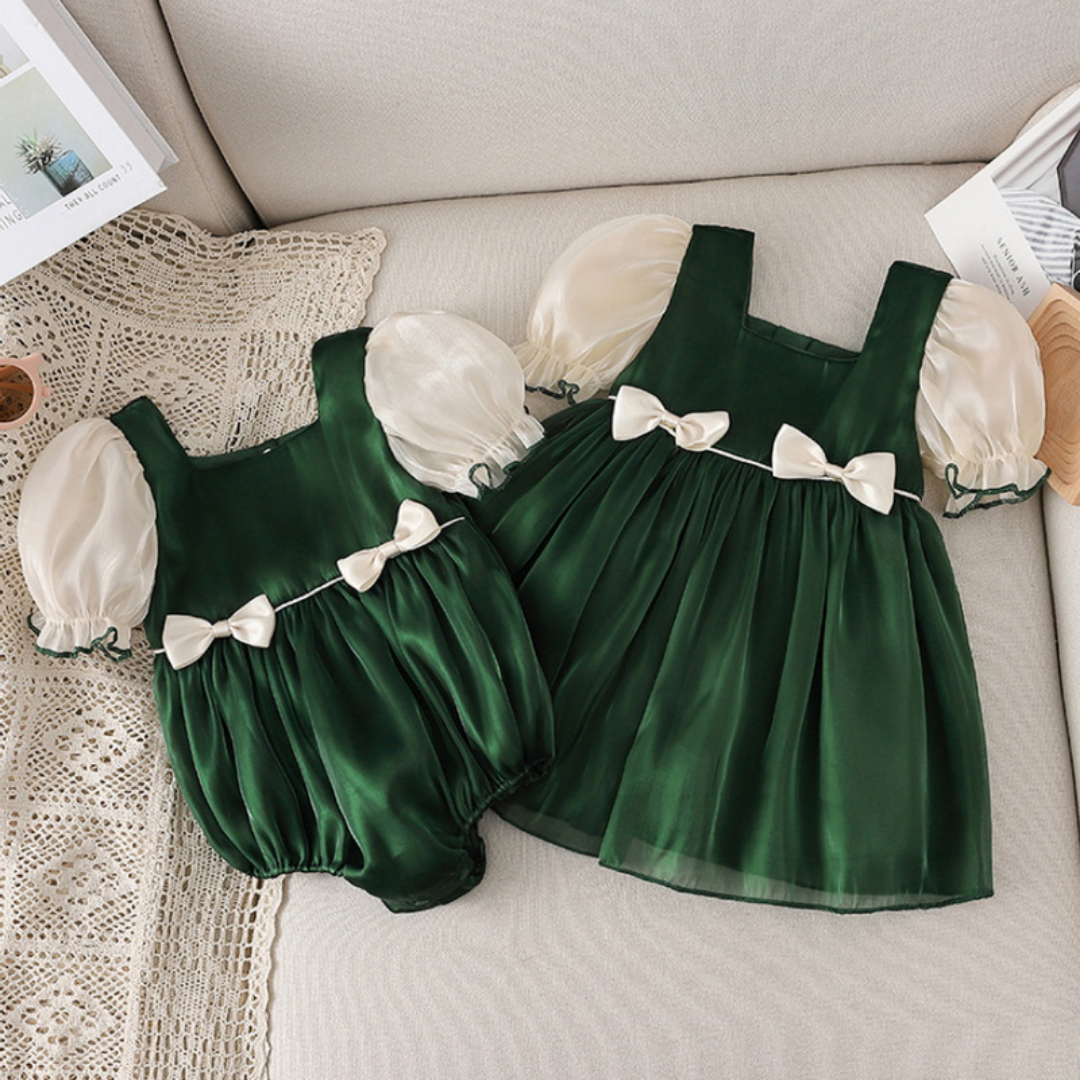 Close-up of bow design & puff sleeves on a girls' pink cotton blend dress, part of a matching set.