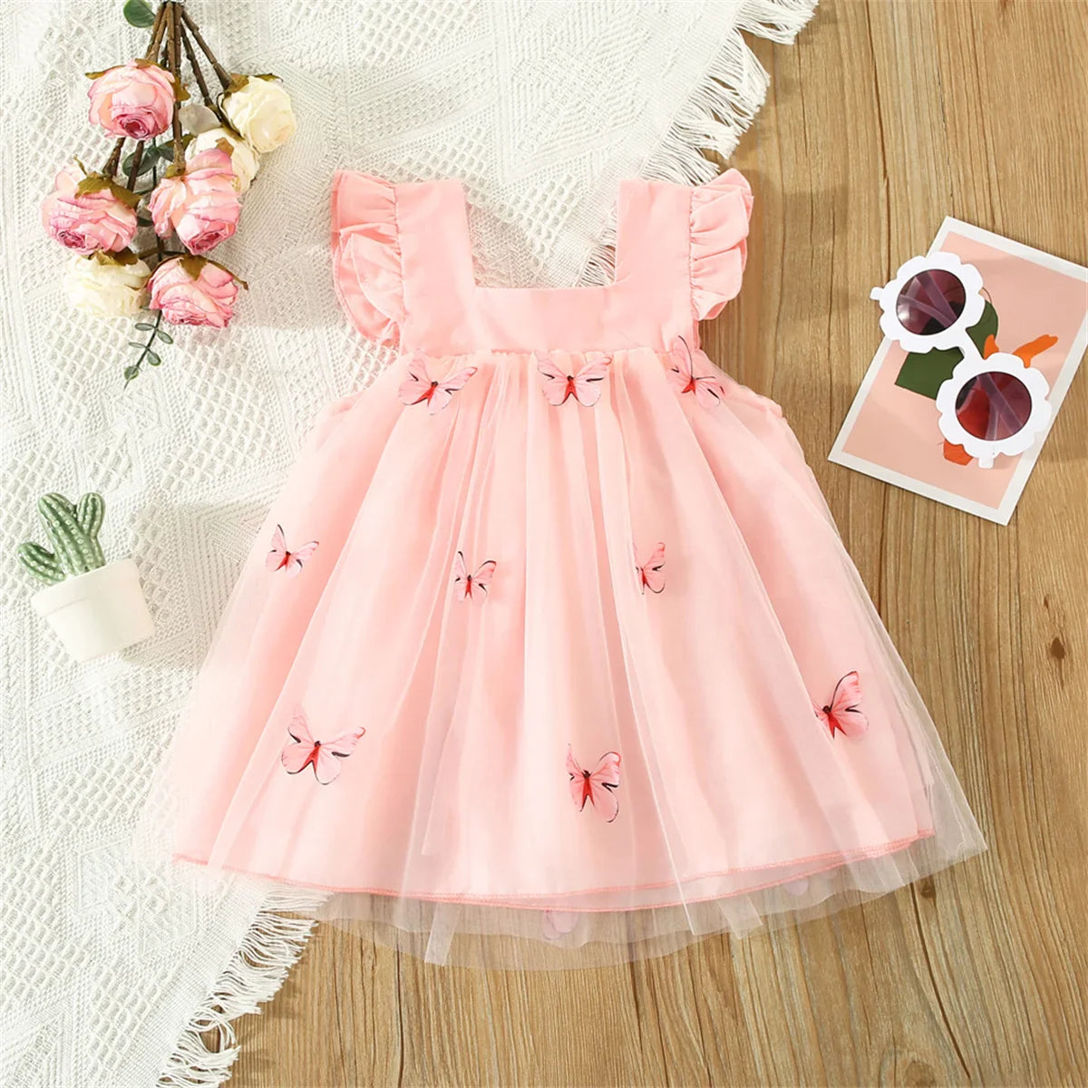 Detailed view of mesh fabric and butterfly design on girls' dress