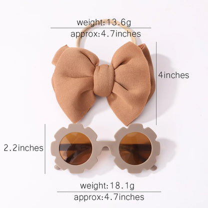 A pair of girls' fashion sunglasses and a soft bow headband, displayed on a clean surface