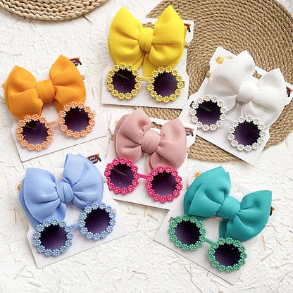 Assortment of girls' sunglasses & bow headband sets, showcasing different color options
