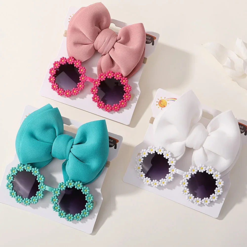 Close-up of girls' sunglasses with floral details and a coordinating pink bow headband