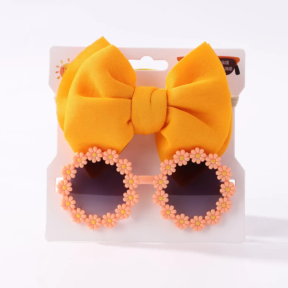 Overhead view of girls' sunglasses and an elastic bow headband, essential summer accessories