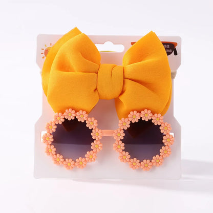 Overhead view of girls' sunglasses and an elastic bow headband, essential summer accessories