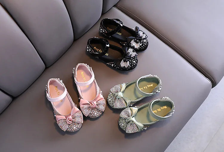 Pair of girls' pink special occasion shoes with a glamorous rhinestone bow design