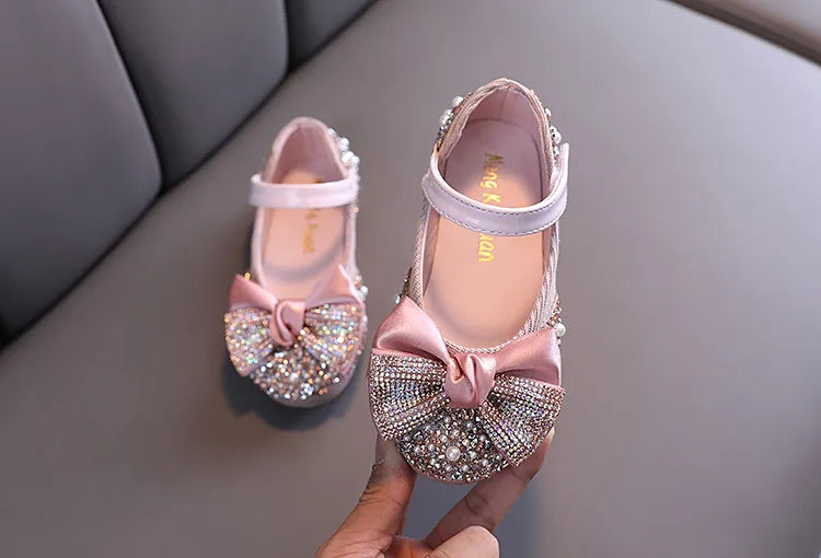 Girls' pink ballet-style flats adorned with a sparkling rhinestone bow, perfect for parties