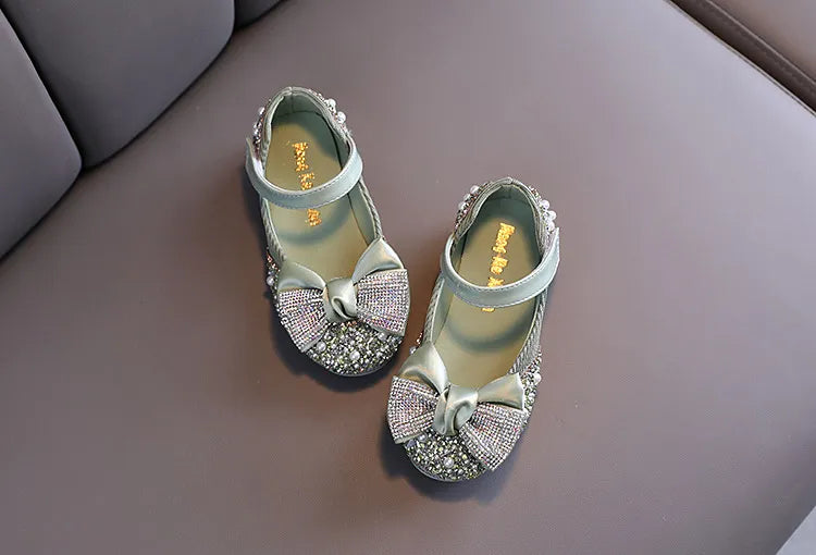 Girls' pink party flats featuring a large, intricate rhinestone bow, perfect for a grand entrance