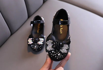 Classic girls' pink dress shoes updated with a dazzling rhinestone bow, elegant and fun