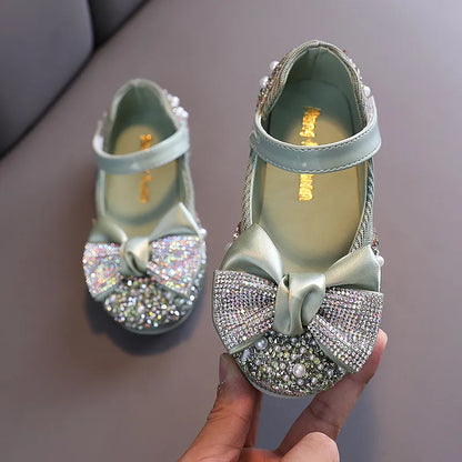 Back view of girls' pink dress shoes with a subtle rhinestone bow, ideal for formal events