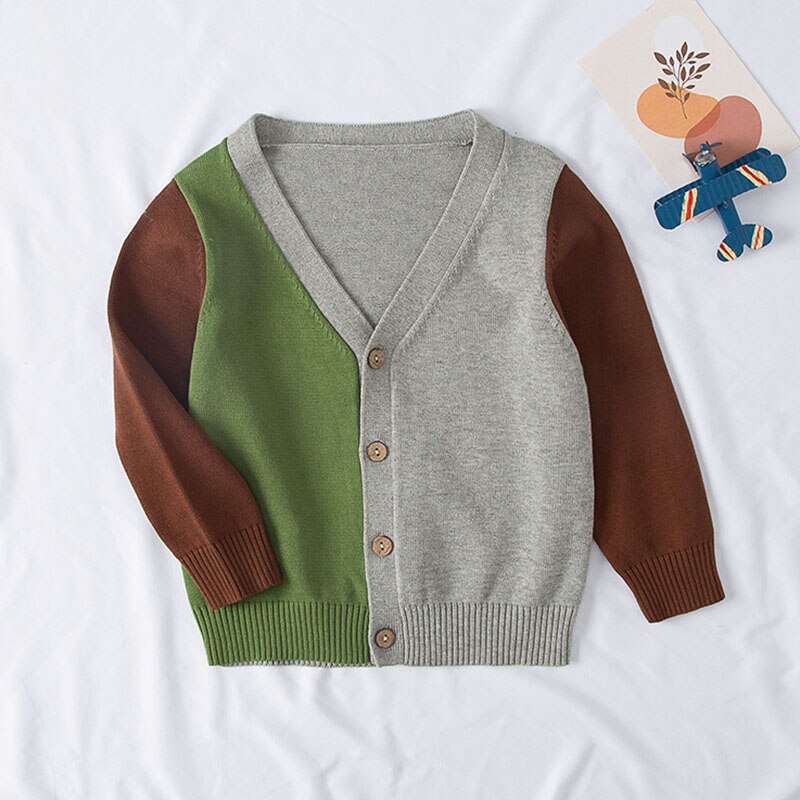 Flat lay of a pink girls' knitted sweater, adorned with a playful pear fruit pattern, fall fashion essential.