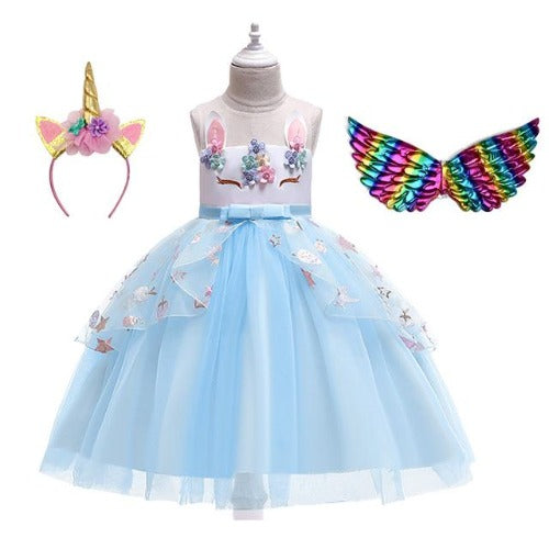 Young girl happily posing in a vibrant unicorn party dress, complete with a horn headband and iridescent wings.