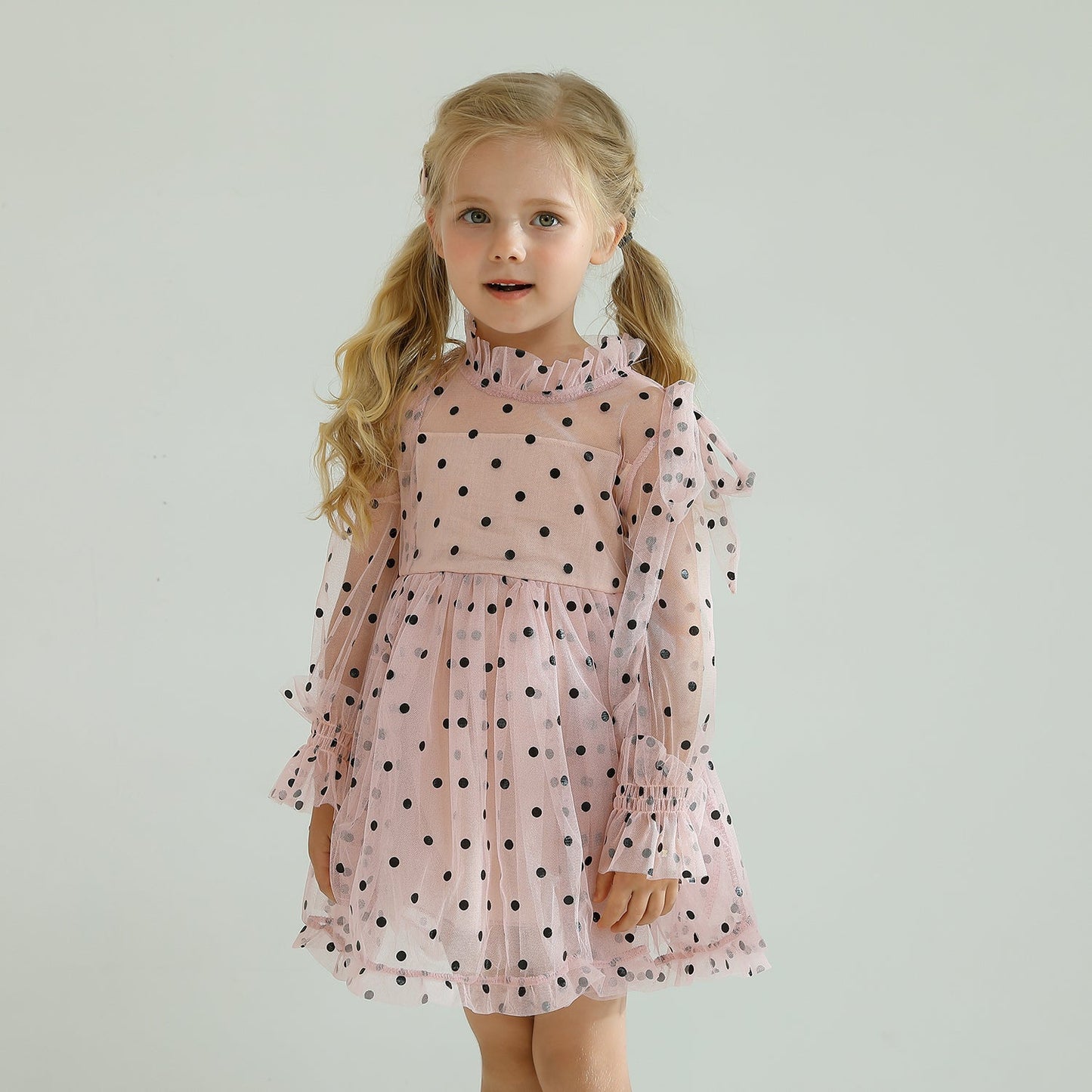 Baby girl in a charming long sleeve dotted mesh ruffled dress, ideal for parties.