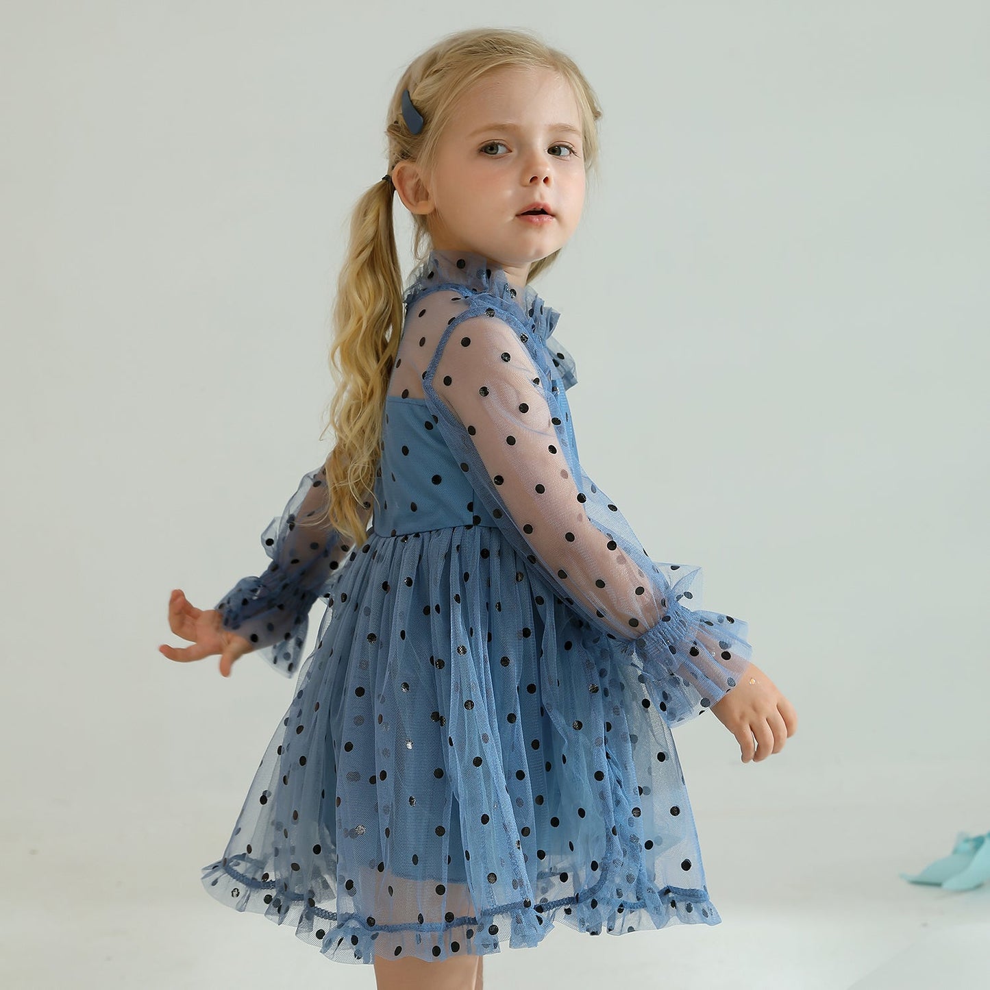Young girl showcasing a beautiful long sleeve dotted mesh ruffled party dress.