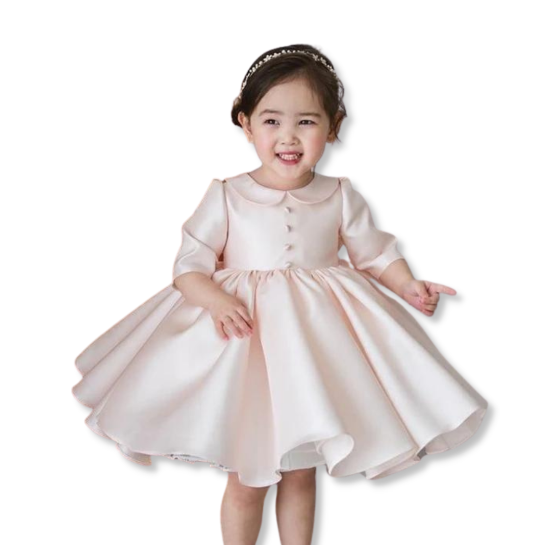 Toddler girl in elegant white long sleeve christening party dress, knee-length, with Peter Pan collar