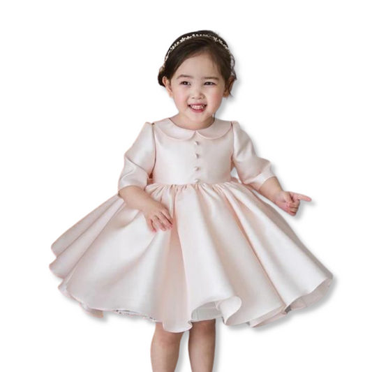 Toddler girl in elegant white long sleeve christening party dress, knee-length, with Peter Pan collar
