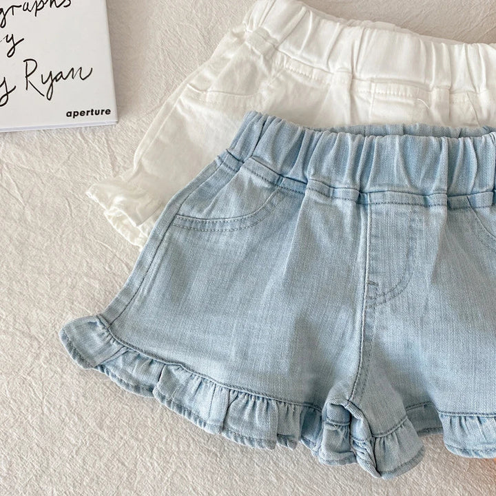 Group of diverse toddlers wearing various colors of cotton ruffle shorts while playing.