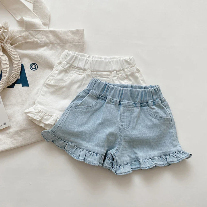 Close-up of white cotton ruffle shorts for baby girls; comfy elastic waist & playful design.