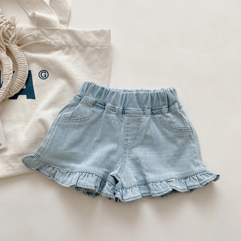 Little girl wearing blue cotton ruffle shorts, perfect for active playtime & summer fun.