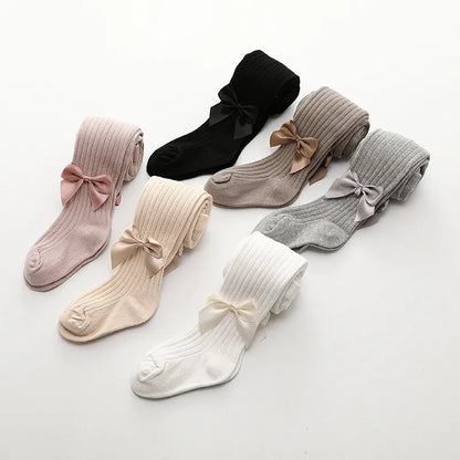 Display of girls' assorted cotton bow socks against a plain background, focus on quality