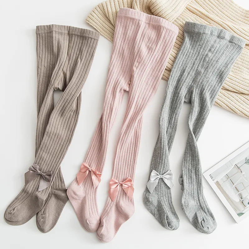 Close-up of white bow detail on a pair of girls' princess pink cotton socks, cute baby accessory