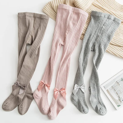 Close-up of white bow detail on a pair of girls' princess pink cotton socks, cute baby accessory