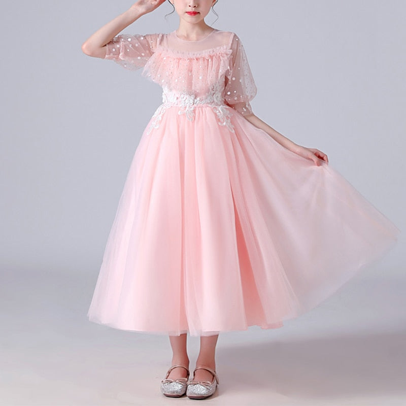 Close-up of a girls' dotted tulle party dress details: sequins, ruffles, and flower appliques