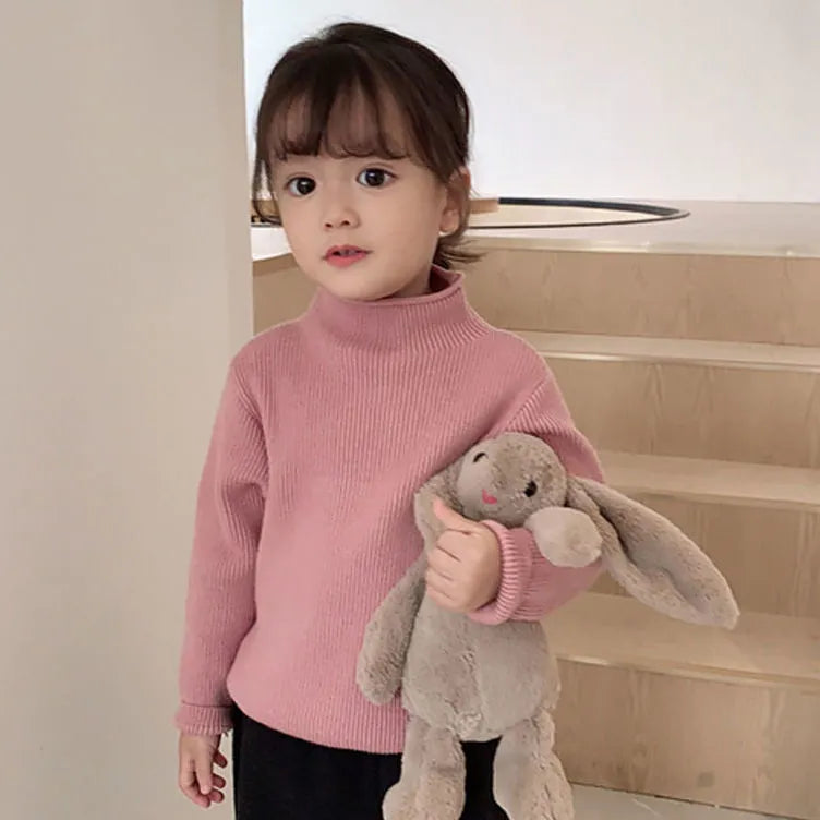 Girls' pink knitted turtleneck sweater styled with jeans, a complete baby girl winter fashion outfit