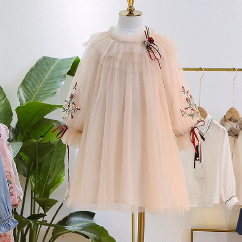 Detailed shot of the puff sleeve and floral lace fabric on a girls' elegant cotton dress.